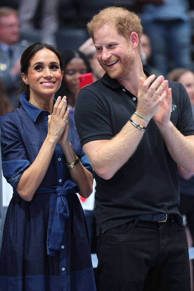 Prince Harry looks at Meghan Markle while clapping hands