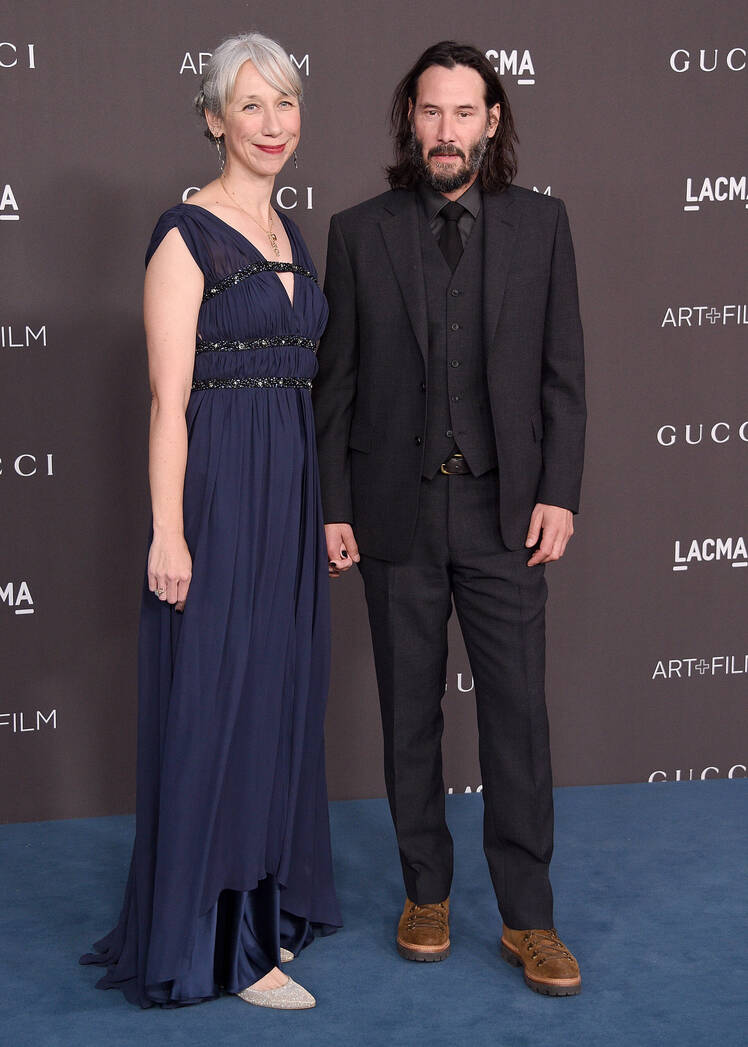 Alexandra Grant wears navy blue gown and Keanu Reeves wears black suit