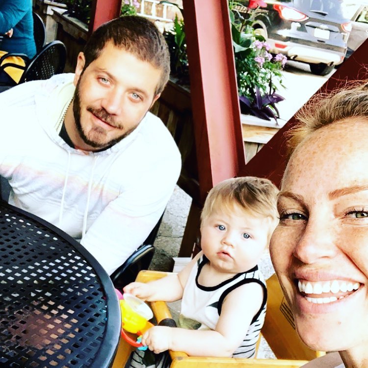 Mina Starsiak Hawk sits with sonJack Hawk and husband Steve Hawk at a table