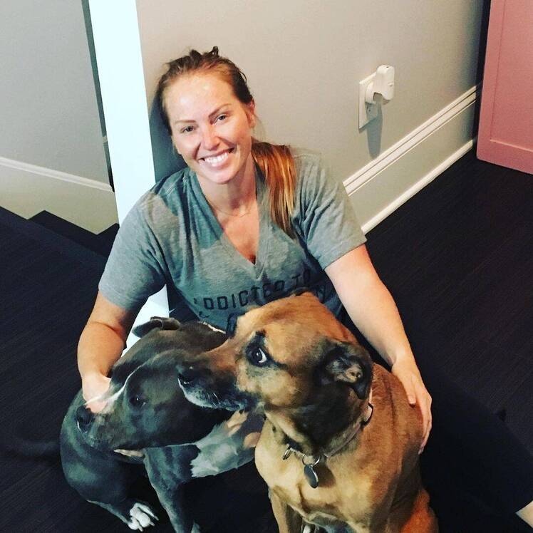 Mina Starsiak Hawk sits on the ground with her dogs