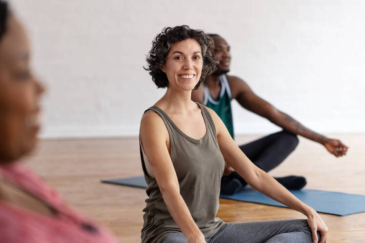 A woman sitting with better posture on a yoga mat