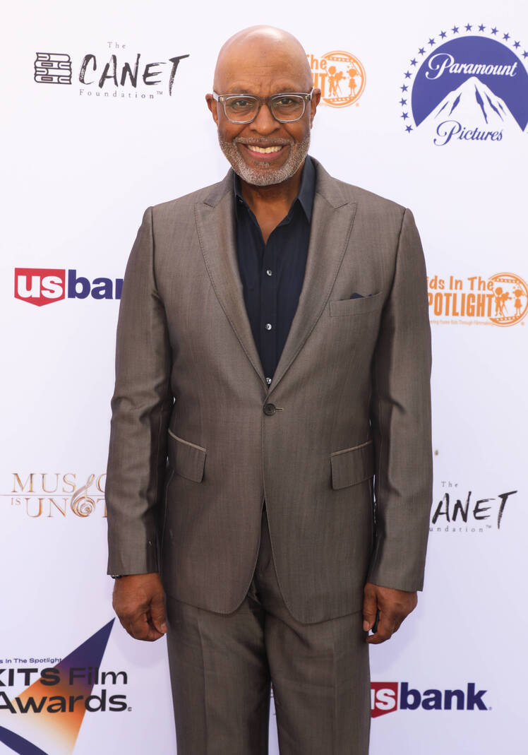 James Pickens Jr. smiles while wearing a gray suit with a black shirt