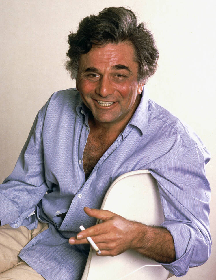 Peter Falk smiles in portrait while smoking a cigarette