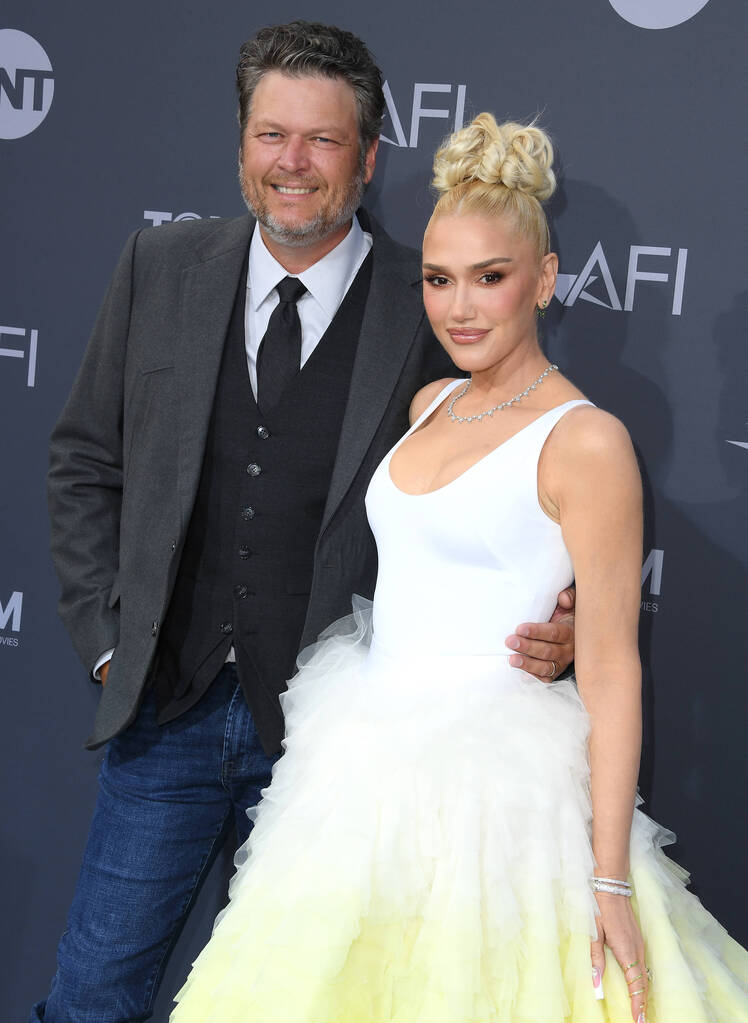 Gwen Stefani smiles in a white and green gown with Blake Shelton