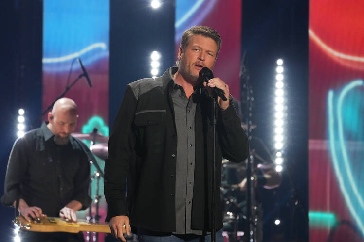 Blake Shelton sings into a microphone on stage