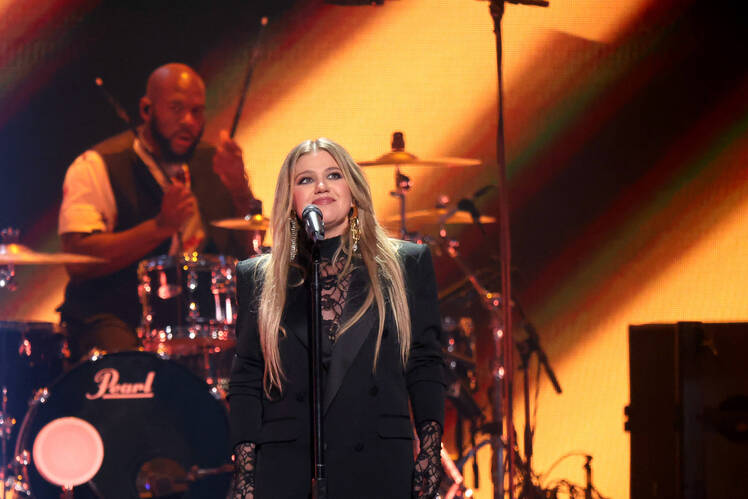 Kelly Clarkson performs on stage in a black blazer