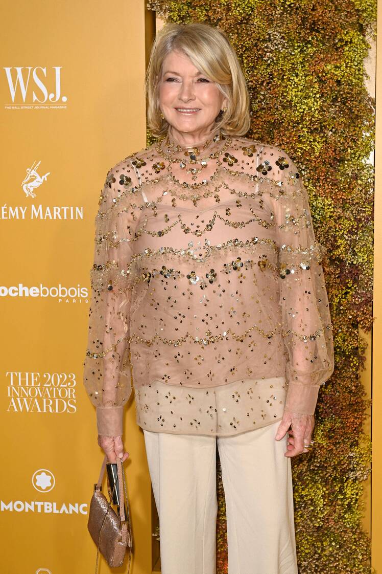 Martha Stewart in a gold blouse and tan pants