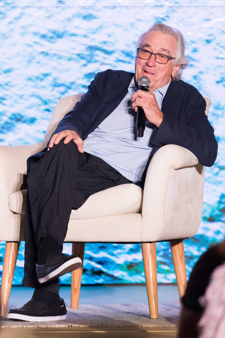 Robert De Niro sits in chair with microphone